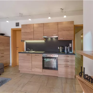 Eine moderne Küche mit Holzschränken, einem Herd und einem Kühlschrank. Der Raum ist hell und freundlich gestaltet.