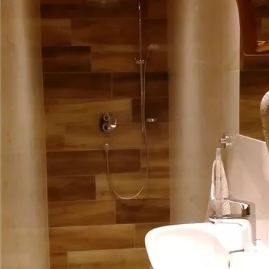 A modern shower with wood paneling and a spacious sink. The walls are designed to be bright and welcoming.