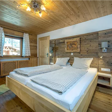 Ein gemütliches Schlafzimmer mit einem Holzdesign und zwei Einzelbetten. Das Zimmer hat große Fenster und eine warme, einladende Atmosphäre.