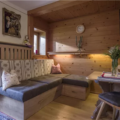 Ein gemütlicher Wohnraum mit Holzverkleidung und einem bequemen Sofa. Auf dem Tisch steht eine Vase mit Blumen und ein Fernseher ist an der Wand montiert.