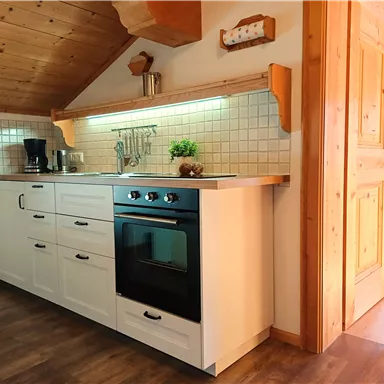 A modern kitchen with white cabinets and a stove. The room has a cozy atmosphere and plenty of daylight.