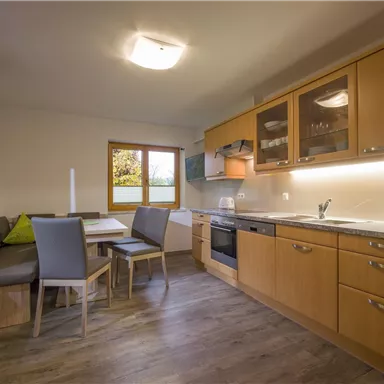 Eine moderne Küche mit Holzschränken und einem Essbereich. Das Zimmer hat ein Fenster mit Blick nach draußen und eine freundliche Atmosphäre.