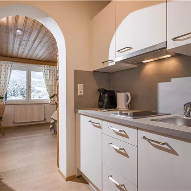 A modern kitchen with bright cabinets and a small window. The room is friendly and well-lit.