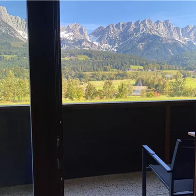 Ein schöner Blick auf die Berge und die grüne Landschaft vom Balkon aus. Die Sonne scheint und der Himmel ist klar.