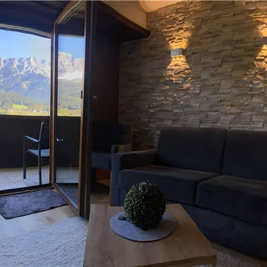 Ein modernes Wohnzimmer mit einem Blick auf die Berge. Der Raum ist hell und einladend, mit einer bequemen Couch und einem kleinen Tisch.