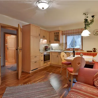 A cozy holiday apartment with a modern kitchen and an inviting living area. Bright wooden paneling and loving decoration create a warm atmosphere.