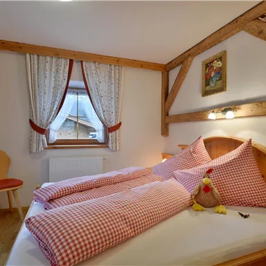 A cozy bedroom with wooden furniture and checkered bedspreads. The atmosphere is warm and inviting.