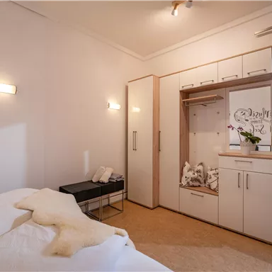 A modern bedroom with a double bed and a wardrobe. The room is bright and friendly, with elegant furnishings.