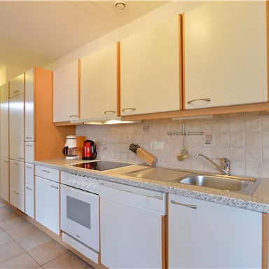 A modern kitchen with bright cabinets and a cozy atmosphere. It is equipped with a sink, stove, and various kitchen appliances.