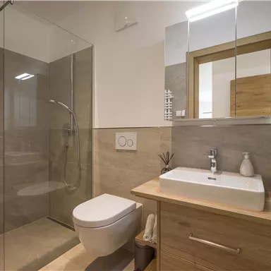 A modern bathroom with a glass shower and a stylish wooden vanity combination. Bright colors and plenty of light create an inviting atmosphere.