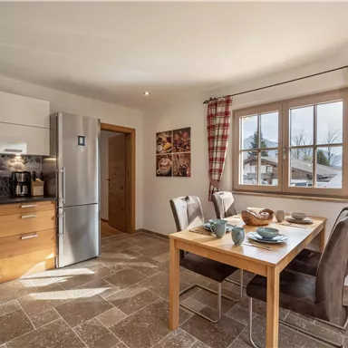 A modern kitchen with wood furniture and a dining table. The space is bright and invites you to linger.