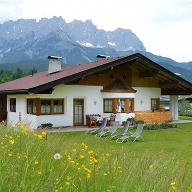 A cozy house with a large garden and a view of the mountains. The landscape is green and inviting, perfect for outdoor relaxation.