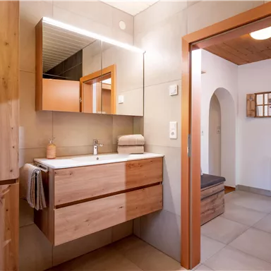 A modern bathroom with wooden shelves and an elegant sink. The warm colors and the clear design create a pleasant atmosphere.