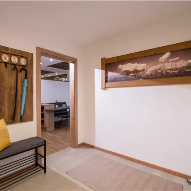 An inviting hallway with a bench and decorations on the wall. On the opposite wall, there is a large picture of mountains.