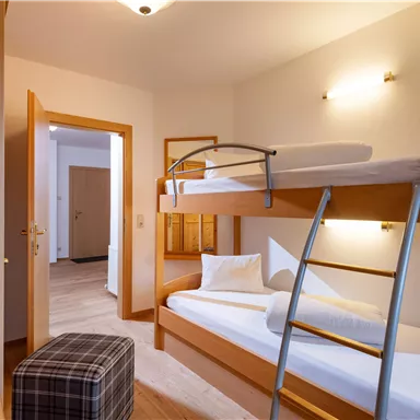 Ein gemütliches Zimmer mit einem Etagenbett und modernem Design. Der Raum verfügt über einen Fernseher und warmes Licht.