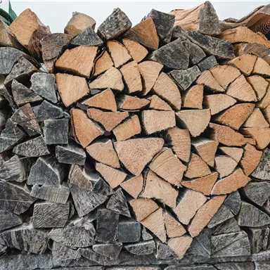 A stack of wood with a heart made of wooden pieces in the center. The wood pieces are neatly stacked, giving the image a warm atmosphere.