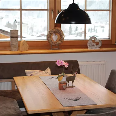 A cozy dining area with a wooden table and comfortable chairs. A snowy landscape can be seen through the windows.