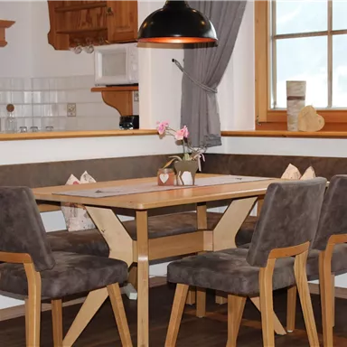 A cozy dining area with a square table and six chairs. A bench provides extra space and a warm atmosphere.