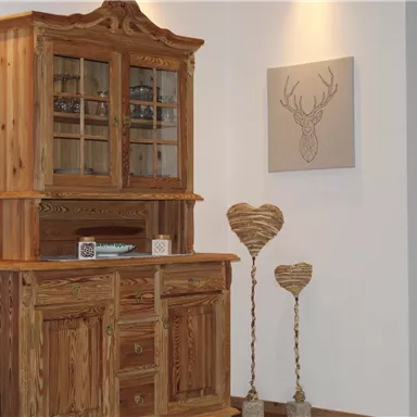 A rustic wooden cabinet ensemble stands against the wall. Below, there are decorative hearts and a picture of a deer silhouette.