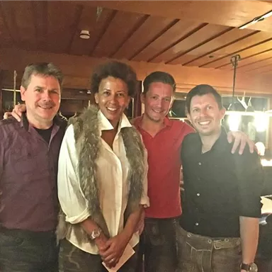 Four people in a cozy restaurant. They are smiling and posing for the picture in a warm, inviting atmosphere.