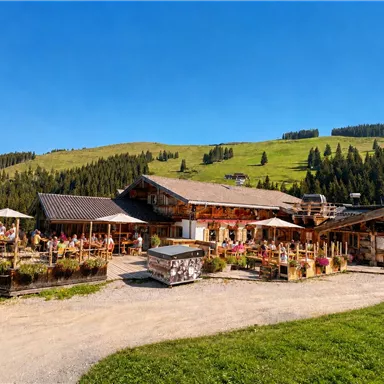 A picturesque mountain restaurant with a beautiful terrace and a view of the green hills. The sunny atmosphere invites you to relax and enjoy.