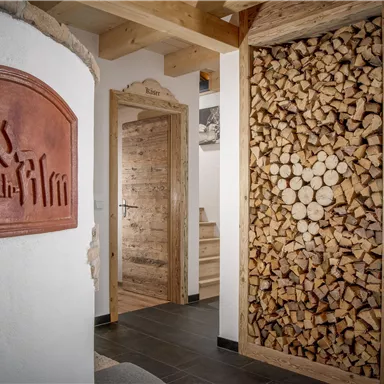 Ein einladender Flur mit einem rustikalen Holzstapel und einem stilvollen Schild. Die Wände sind in neutralen Tönen gehalten, und die Holzelemente verleihen eine gemütliche Atmosphäre.