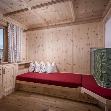 Ein gemütlicher Raum mit Holzvertäfelung und einem roten Sofa. Ein Fenster bietet einen Ausblick auf die Landschaft.