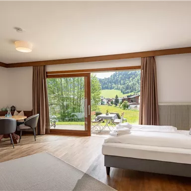 Ein modernes Zimmer mit zwei Einzelbetten und Blick auf die grüne Landschaft. Große Fenster lassen viel Licht herein und schaffen eine einladende Atmosphäre.