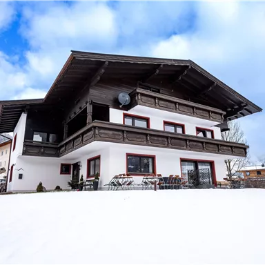 Ein schönes Chalet im Schnee mit einem großen Balkon. Der Himmel ist klar und die Umgebung ist malerisch.