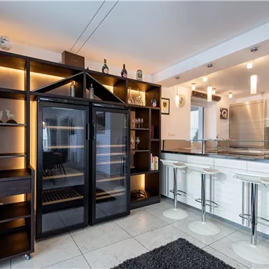 A modern kitchen with an elegant cooking area and an open shelf. The space is well-lit and has a stylish, contemporary design.