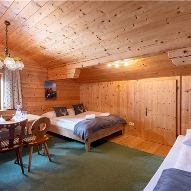 A cozy wooden room with two beds and a dining table.  
Large windows let in plenty of light and offer a beautiful view of the surroundings.