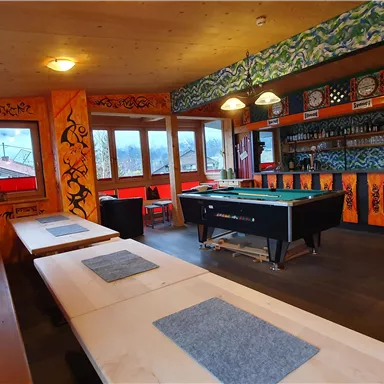 A cozy room with colorful walls and a billiard table. Tables and benches provide space for relaxing and playing.