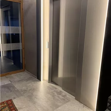 A modern elevator in an elegant space. The floor is laid with gray tiles and a carpet complements the furnishings.