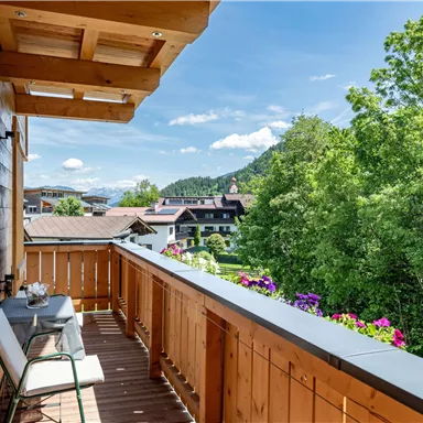 A beautiful balcony with wood paneling and a view of nature. Colorful flowers and a picturesque landscape create a cozy atmosphere.