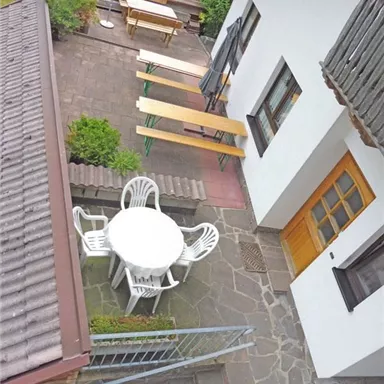 Ein gemütlicher Außenbereich mit einem runden Tisch und Stühlen. Im Hintergrund stehen mehrere Bänke und eine gemütliche Atmosphäre.