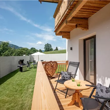 A beautiful balcony with a wooden railing and a view of the green landscape. Two chairs and a table invite you to relax.