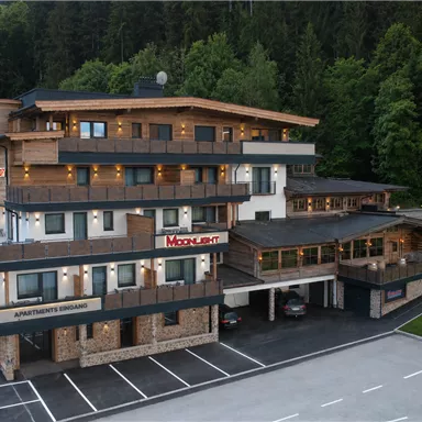 Ein modernes Gebäude mit Holzverkleidung inmitten von Bäumen. Es bietet Apartments und liegt in einer ruhigen Umgebung.