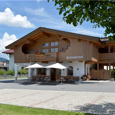 A cozy wooden house with a balcony and outdoor umbrellas. Surrounded by a beautiful landscape and a clear blue sky.