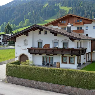 A stylish house in the mountains with a cozy balcony. Surrounded by green meadows and majestic mountains.