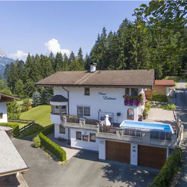 Ein charmantes Haus in einer malerischen Berglandschaft. Der Garten ist gepflegt und ein Pool ergänzt die entspannte Atmosphäre.