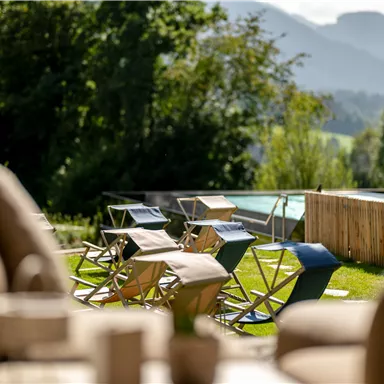 Eine entspannte Terrasse mit Liegestühlen und einem Blick auf die Berge. Der Pool im Hintergrund lädt zum Entspannen ein.
