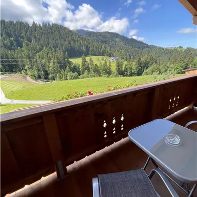 A beautiful view from a balcony of a green mountain landscape. The sky is blue with a few clouds.