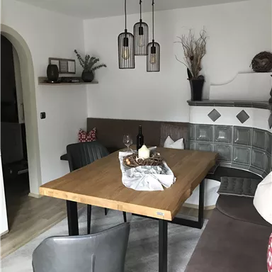Ein gemütlicher Essbereich mit einem Holzstammtisch und modernen Stühlen. Im Hintergrund sind dekorative Elemente und eine gemütliche Sitzecke zu sehen.
