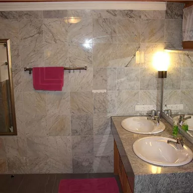 Ein modernes Badezimmer mit zwei Waschbecken und großem Spiegel, Badewanne, Dusche und WC