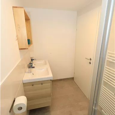 A modern bathroom with a bright design. It features a sink, a mirror, and a shower.