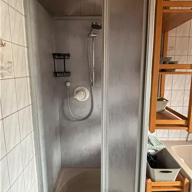 Eine moderne Dusche mit gläserner Trennwand. Sie befindet sich in einem Badezimmer und ist sauber und praktisch gestaltet.