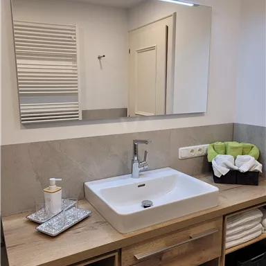 A modern bathroom with an elegant sink and a large mirror. The wooden surface and fresh towels give the space an inviting atmosphere.