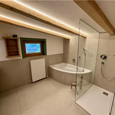 A modern bathroom with a shower and a bathtub.
Bright colors and wooden details create a pleasant atmosphere.