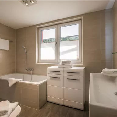 A modern bathroom with a bathtub, a shower, and a sink. Bright colors and elegant furniture create an inviting atmosphere.