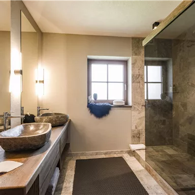 A modern bathroom with elegant fixtures and a spacious shower area. Large windows provide plenty of daylight and a pleasant atmosphere.